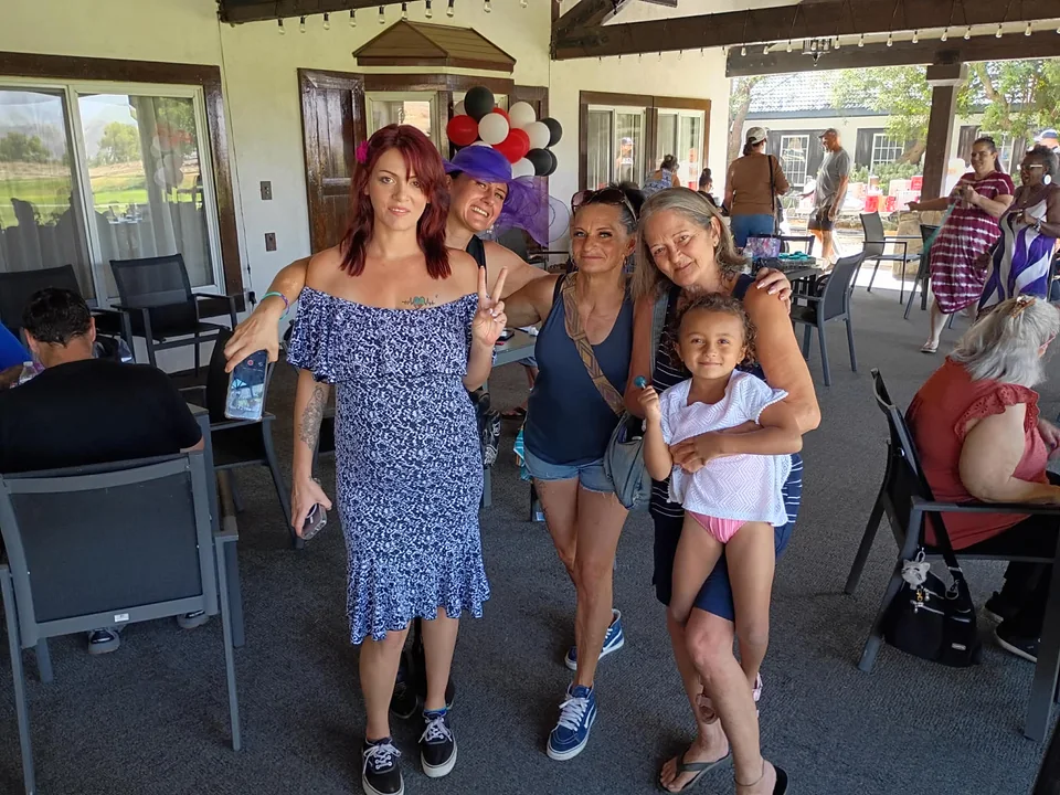 Four adults and a child posing together on the decorated patio at Extravaganza 2026.