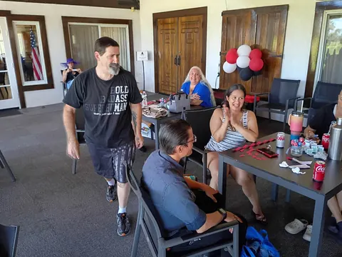Guests talking beside a patio table scattered with red raffle tickets.