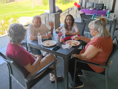 Four guests sharing food and conversation around a patio table.