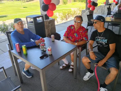 Three guests seated at a patio table with raffle tickets and drinks.